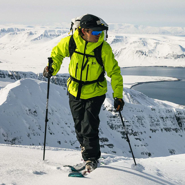 Person skiing on a snowy mountain with a scenic view of snow-covered mountains and a lake.