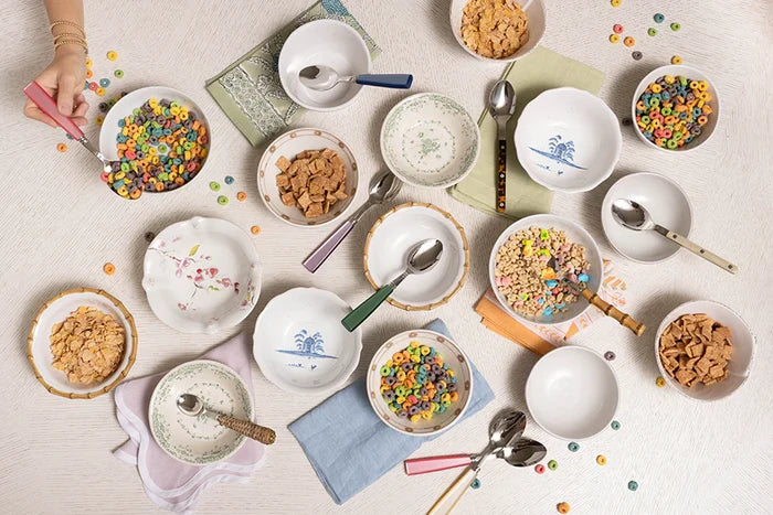 Cornflower blue linen napkins with delicate embroidered designs, styled with white ceramic bowls and colorful cereal on a.