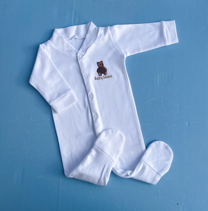 White baby onesie with a teddy bear design on a blue background