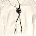 Two bear paw bolo ties with black braided leather cords: silver-tone faux turquoise bear claw slider and black stone bear paw pendant with antique metal tips.