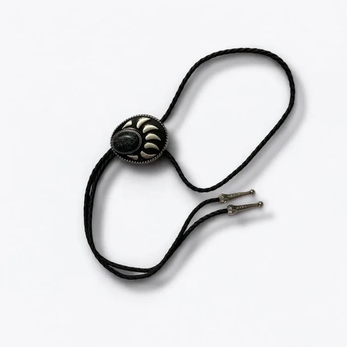 Two bear paw bolo ties with black braided leather cords: silver-tone faux turquoise bear claw slider and black stone bear paw pendant with antique metal tips.