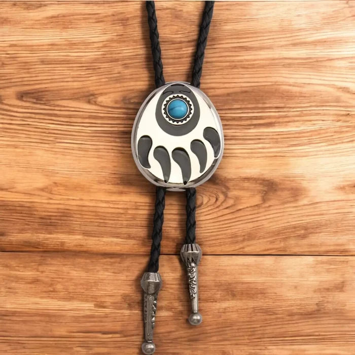 Two bear paw bolo ties with black braided leather cords: silver-tone faux turquoise bear claw slider and black stone bear paw pendant with antique metal tips.