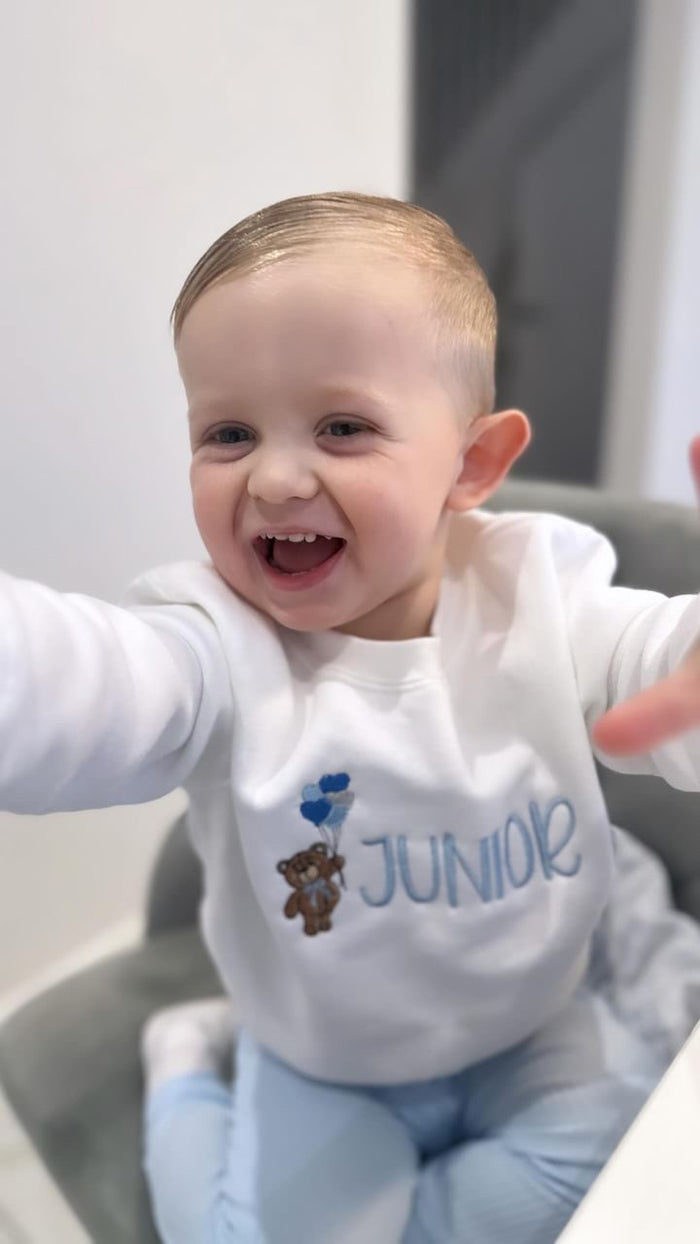 Boy wearing sweatshirt with teddy bear holding heart balloons jumper