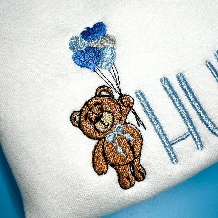 Close of up embroidered beat holding heart balloons