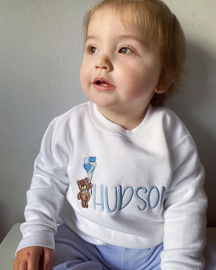 Boys wearing White jumper with teddy bear holding heart ball balloons embroidered on the front along with a name