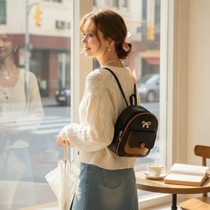 lifestyle woman shopping wearing Black Brown Trim Mini Backpack with gold bow detail and adjustable straps / one size