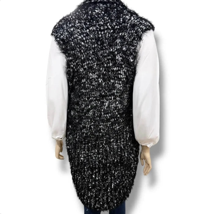 Black and white marled chunky fuzzy knit sleeveless cardigan vest with open front, rolled collar, and rounded high-low shirttail hem in sizes small and medium
