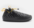 Black slip-on shoe with yellow accents on a white background
