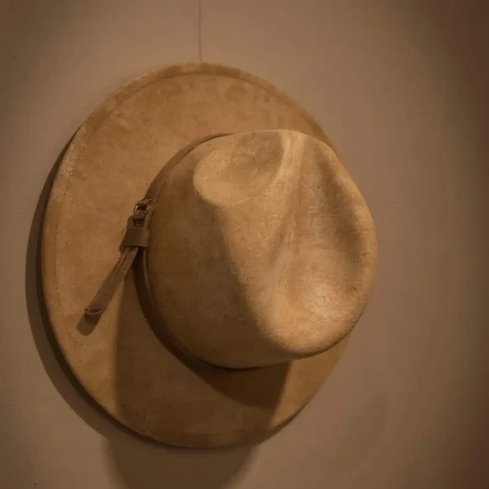 Brown suede fedora hat hanging on a wall
