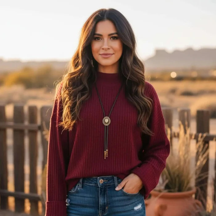 woman wearing a burgundy mock neck rib knitted sweater with wide cuff sleeves