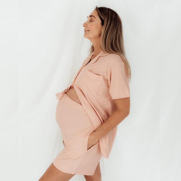 Side profile of a mum-to-be in pink Sleepybelly maternity pyjamas with the top open over her bump
