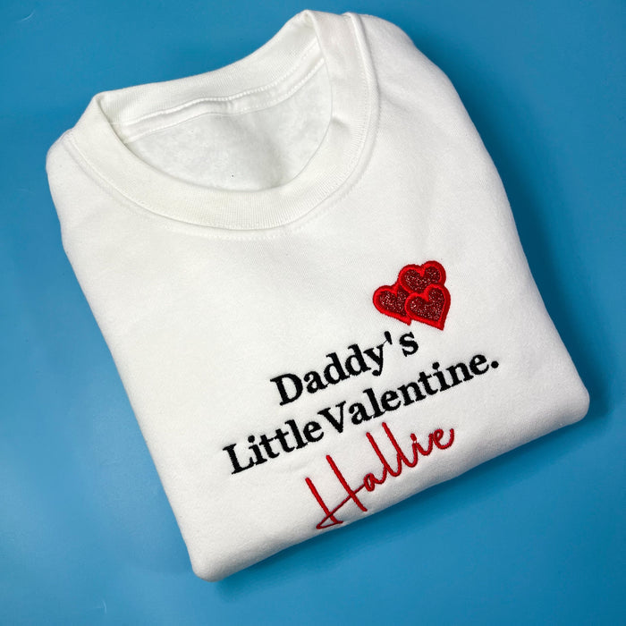 Daddy’s/mummy’s little valentine sweatshirt is a white jumper with bland and red embroidery and a glitter heart