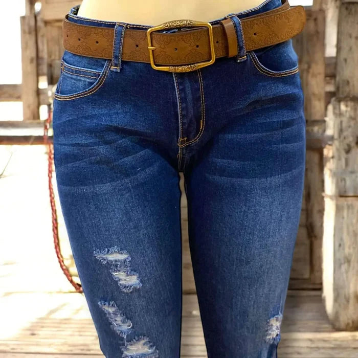 Women's Dark Brown Floral Brass Buckle Belt model wearing with jeans rustic background