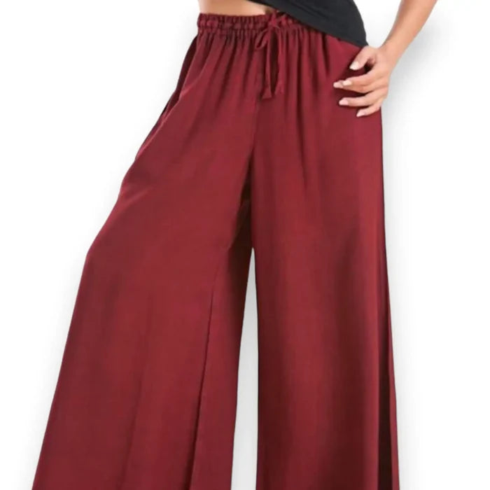 Woman wearing burgundy red wide-leg palazzo pants on a boho city stroll, styled with a relaxed top and sandals for a breezy streetwear look.