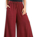 Woman wearing burgundy red wide-leg palazzo pants on a boho city stroll, styled with a relaxed top and sandals for a breezy streetwear look.