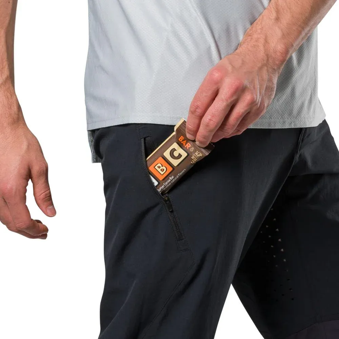 Person wearing black pants with a box of Gatorade in the pocket on a white background