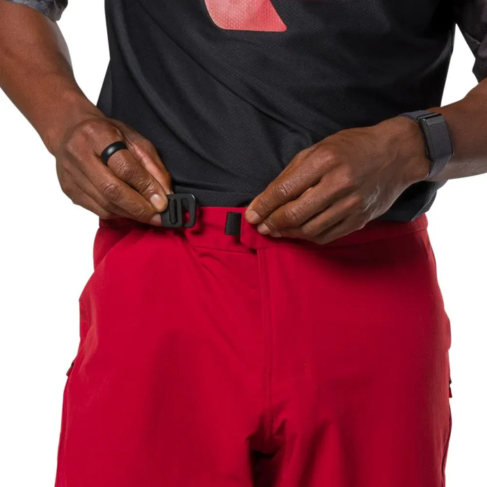 Person wearing a black shirt and red pants adjusting a black belt.