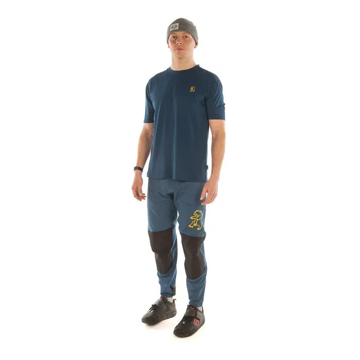 Man wearing a navy blue t-shirt and blue pants with a logo on a white background