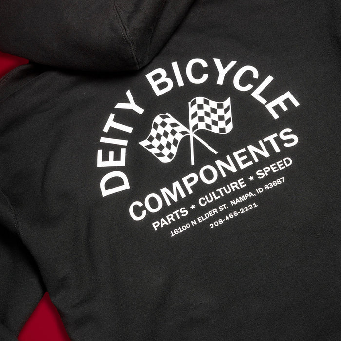 Close-up of a black hoodie showing the back graphic with white text reading 'DEITY BICYCLE COMPONENTS' and two checkered flags, with red fabric visible along the sides.