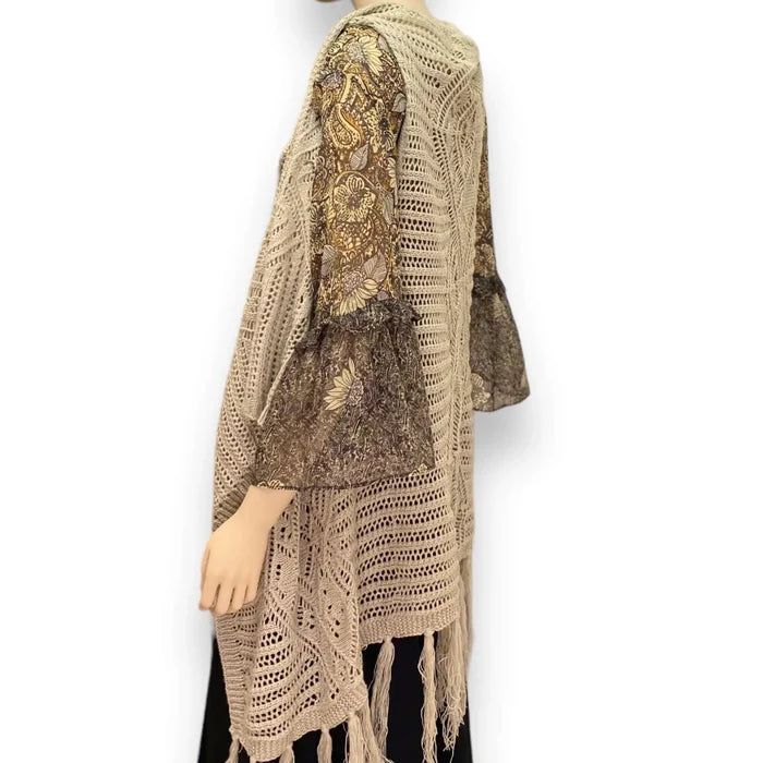 Fringe knitted sleeveless cardigan vest in tan with crochet knit texture, metallic thread accents, open front, and asymmetrical fringe hem