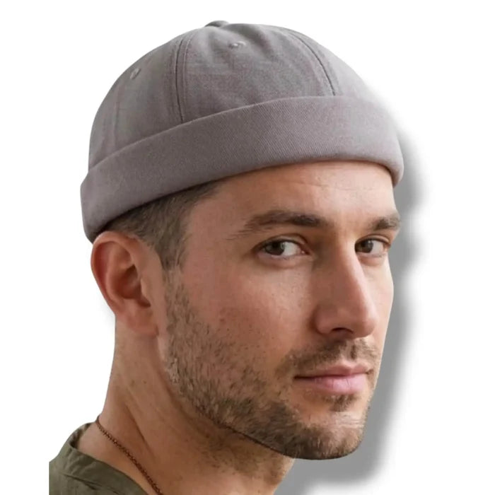 model wearings Harbour Cotton Docker No Brim Cap in gray rolled edge, eyelets, button top, and adjustable strap osfm / unisex