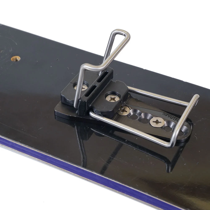 Metal clip or latch on a black surface with a white background