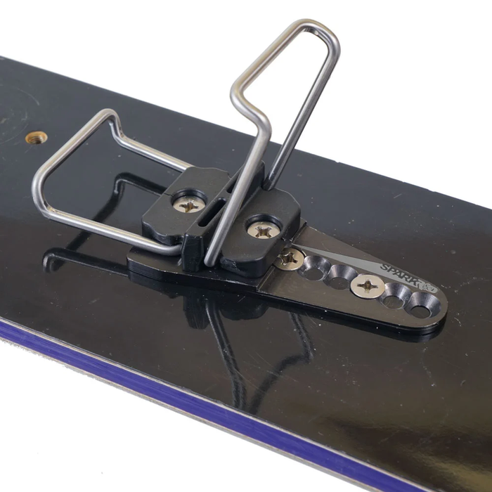 Metallic ski binging on a black surface with a white background