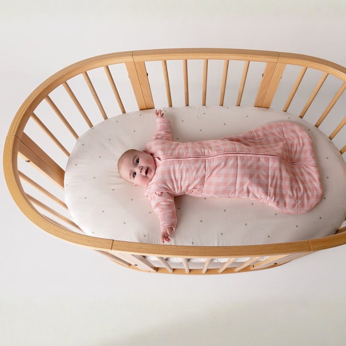 Baby safely dressed in the cot wearing a Sleepybelly Infant Sleeping Bag, illustrating the comfortable fit of this organic cotton sleep sack for transitioning from swaddles