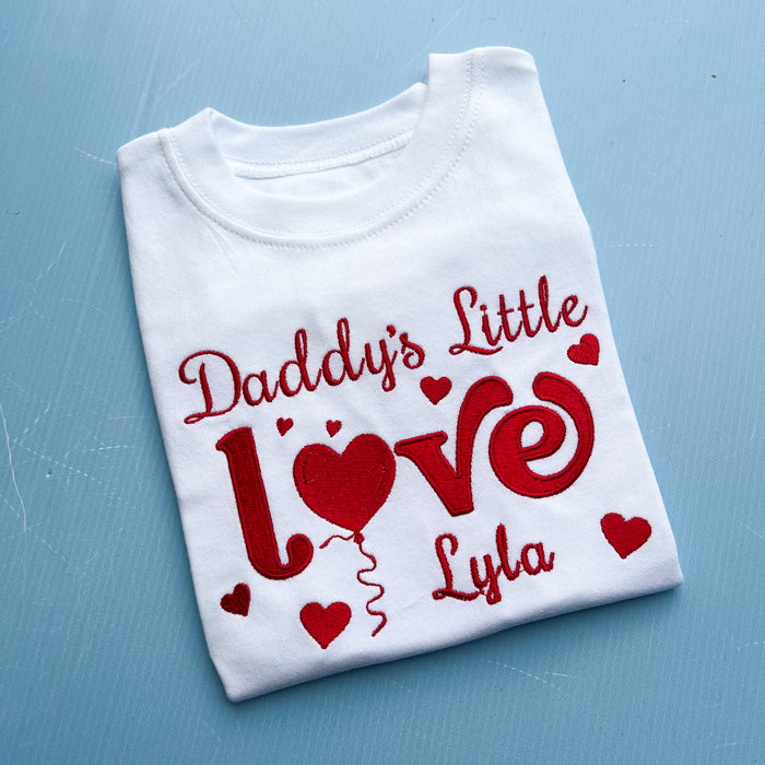 Folded white t-shirt with red text and hearts on a blue background