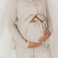 Close-up of a mum-to-be cradling her bump in the buttoned linen grey long sleeve maternity pyjama top