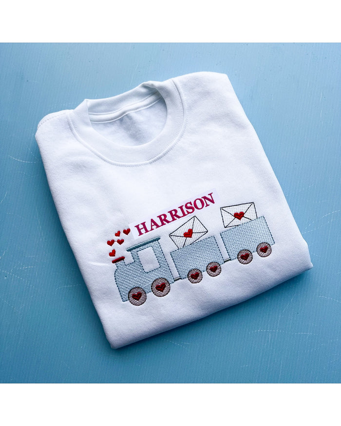 White sweatshirt with embroidered design and name 'HARRISON' on a blue background