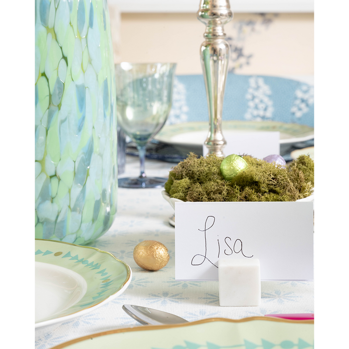 White marble place card holder with handwritten "Lisa" card on a decorated tabletop.
