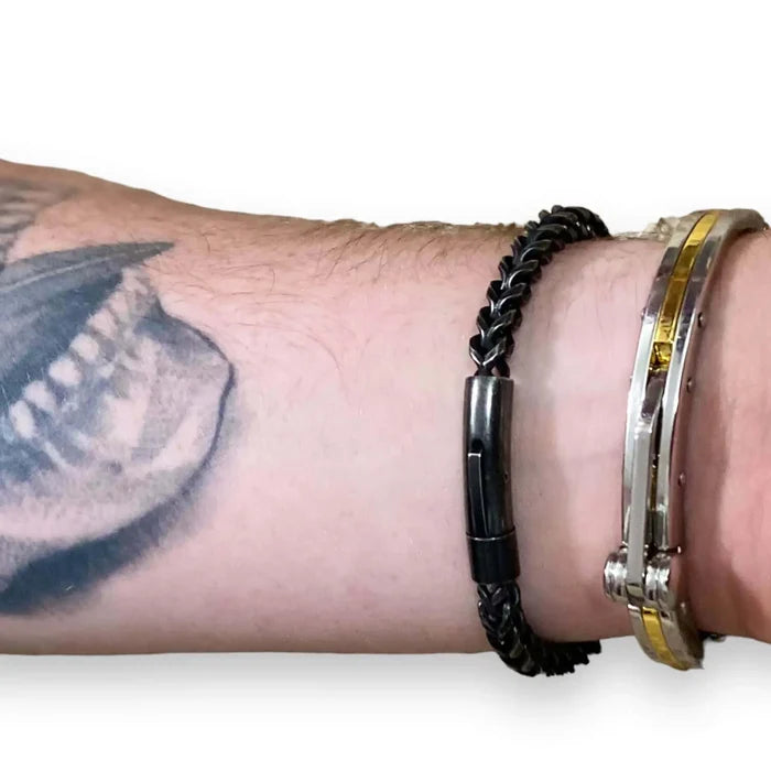Men's Black Metal Rope Moto Bangle worn on a tattooed wrist, showcasing its twisted rope design and polished finish.