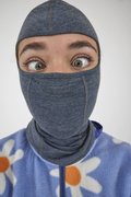 Person wearing a gray balaclava over a colorful sweater with floral patterns.