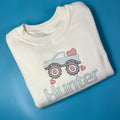 White sweatshirt with a monster truck on the front with love hearts in embroidery