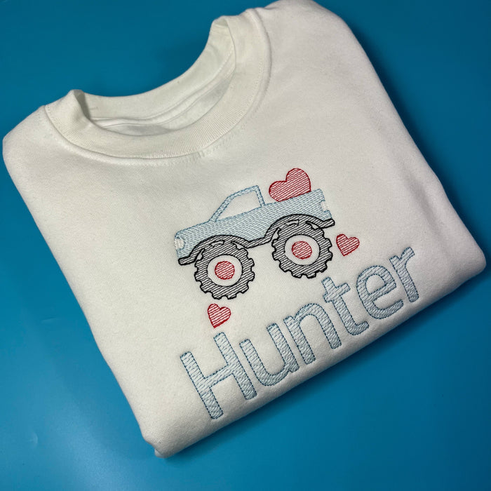 White sweatshirt with a monster truck on the front with love hearts in embroidery