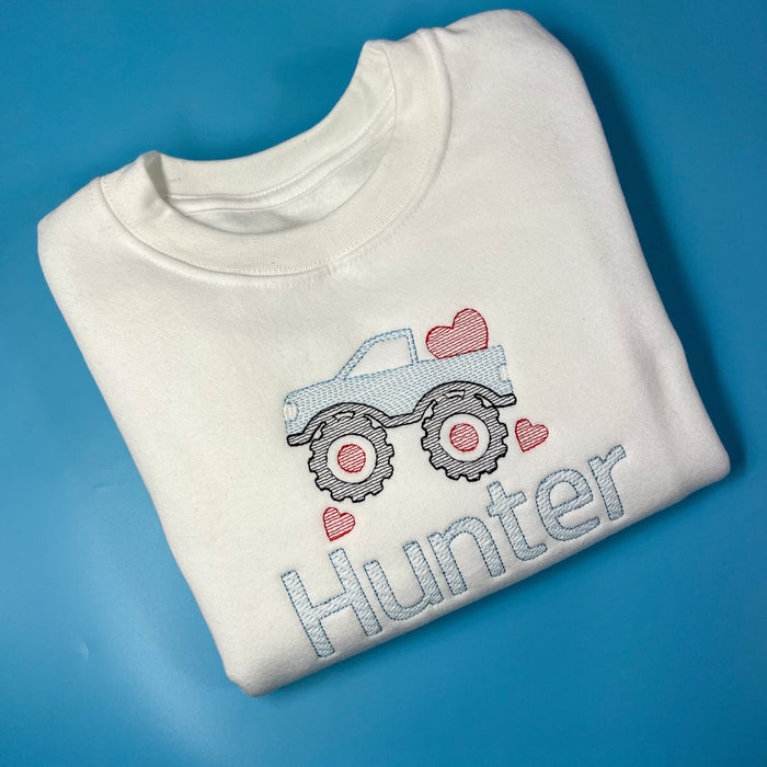 White sweatshirt with a monster truck on the front with love hearts in embroidery
