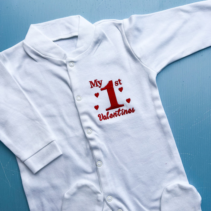 White baby onesie with 'My 1st Valentine' text on a blue background