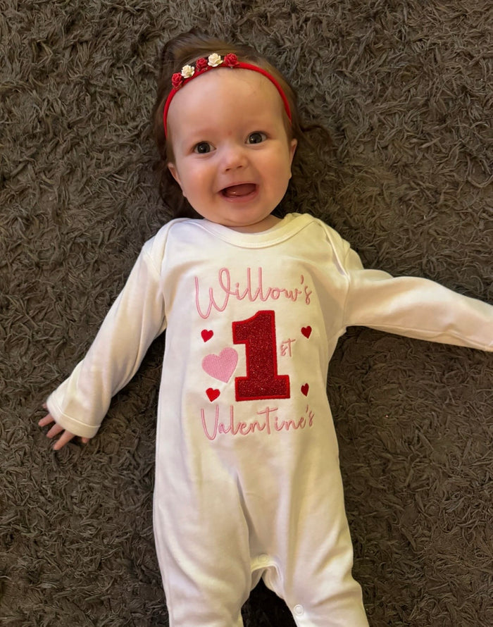 Baby wearing a Valentine's Day-themed onesie on a brown carpet