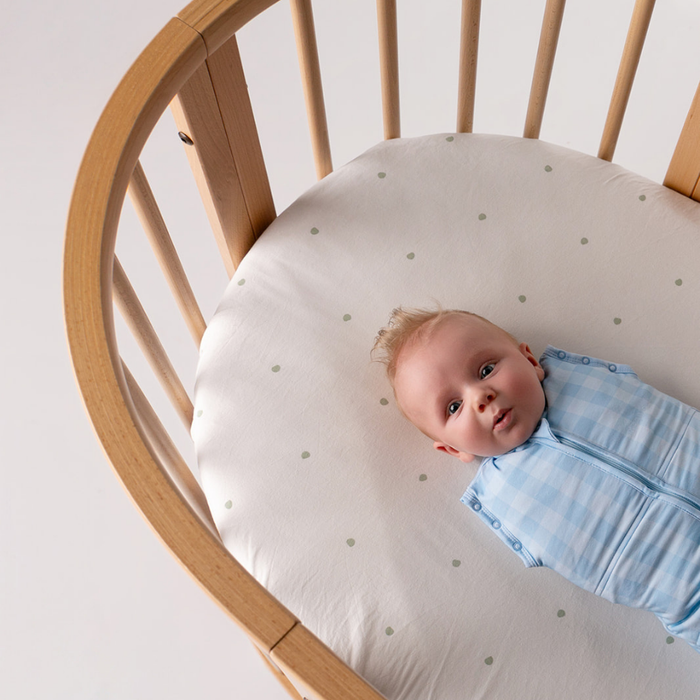 Baby sleeping in swaddle bag mode with arms tucked in, showing the snug fit of our newborn sleep sack.