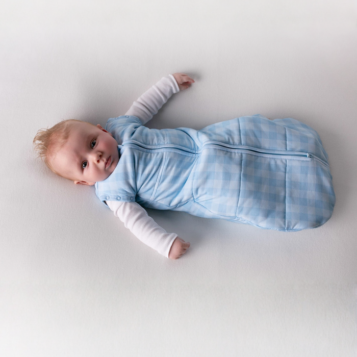 Baby lying on its back in the blue gingham newborn swaddle sack with arms out