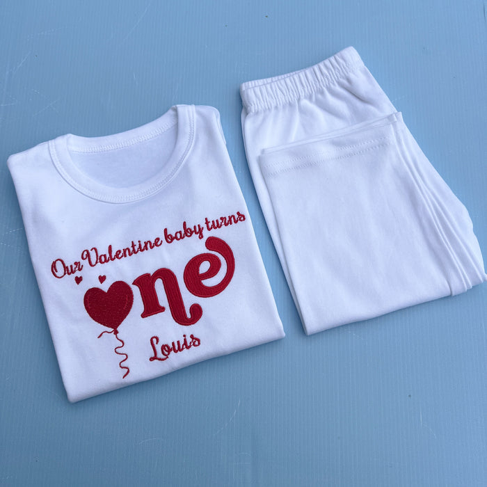 White t-shirt with red text and heart design on a blue background