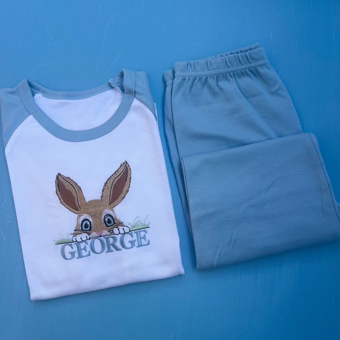 Blue pyjamas with a peaking bunny posting over grass embroidered on with the name George