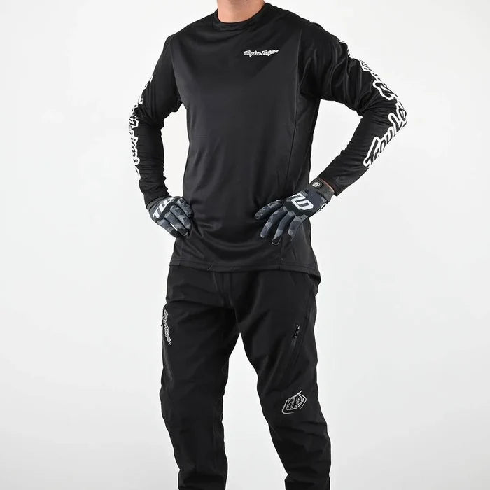 Person wearing a black motocross outfit with gloves on a white background