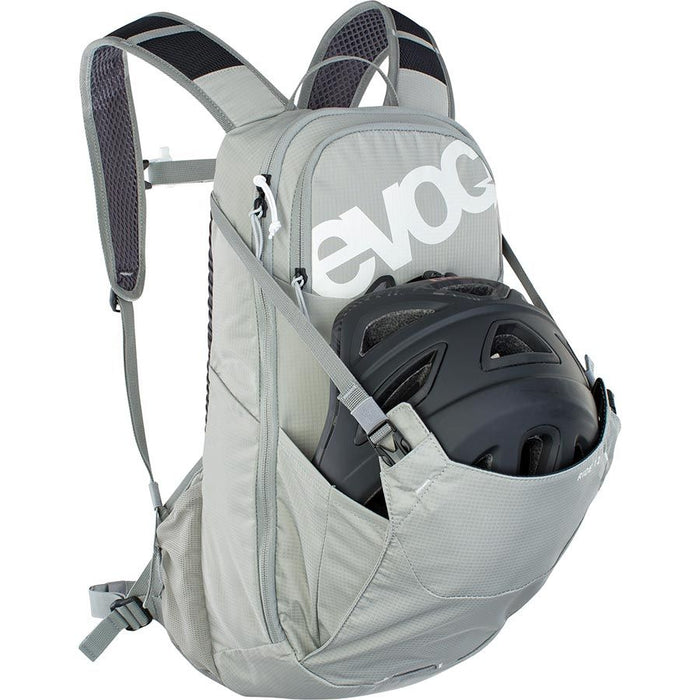 Gray backpack with a helmet inside, featuring the EVOC brand logo.