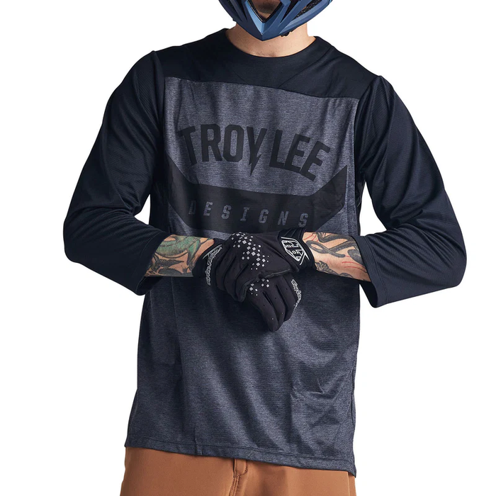Person wearing a Troy Lee Designs long-sleeve shirt and gloves on a white background