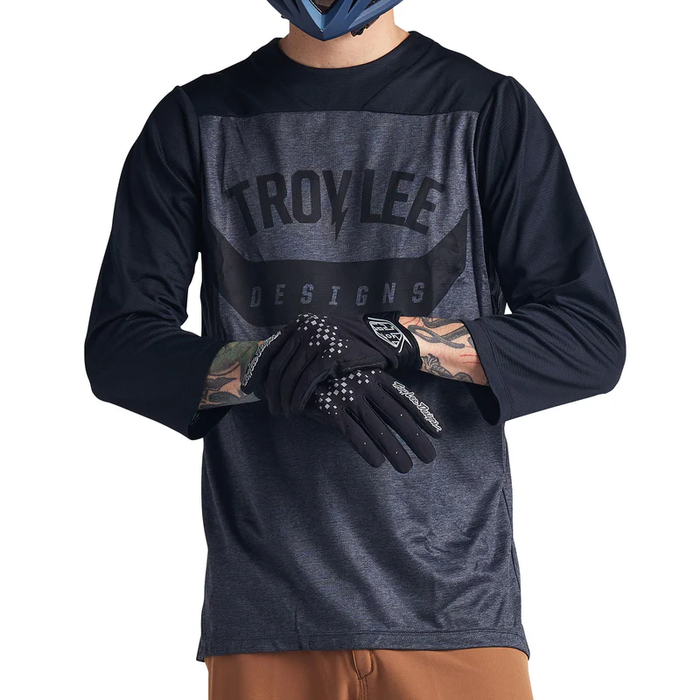 Person wearing a Troy Lee Designs long-sleeve shirt and gloves on a white background