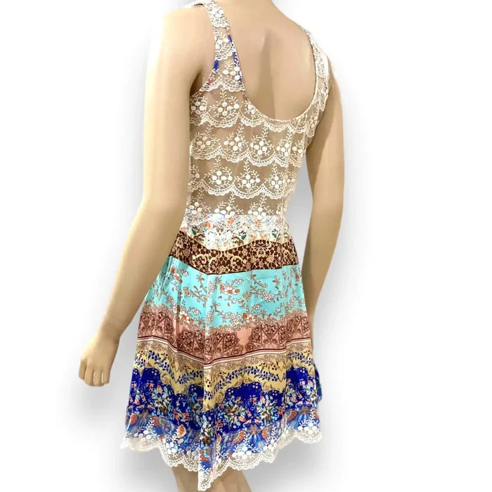 Elegant sleeveless patchwork mini dress with ivory embroidered round neckline, sheer lace back panel, and lace-trim hem in multicolor boho print