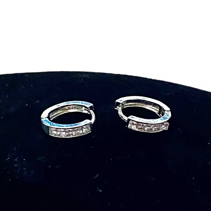 flat lay Silver Crystal Hinge Hoop Earrings with channel-set zirconia, huggie shape, and secure click-latch closure