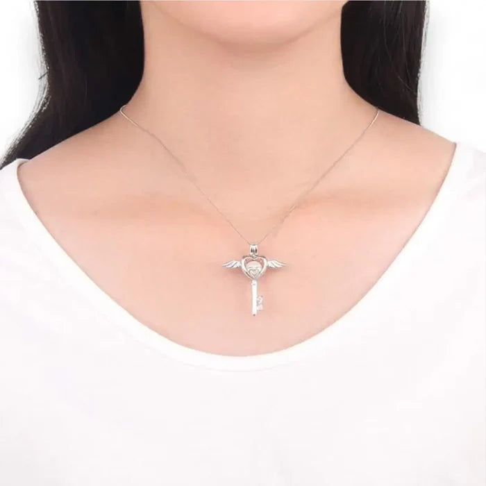 Close-up of silver heart wings key locket necklace with faux pearl and “LOVE” key detail on 16-inch sterling silver chain